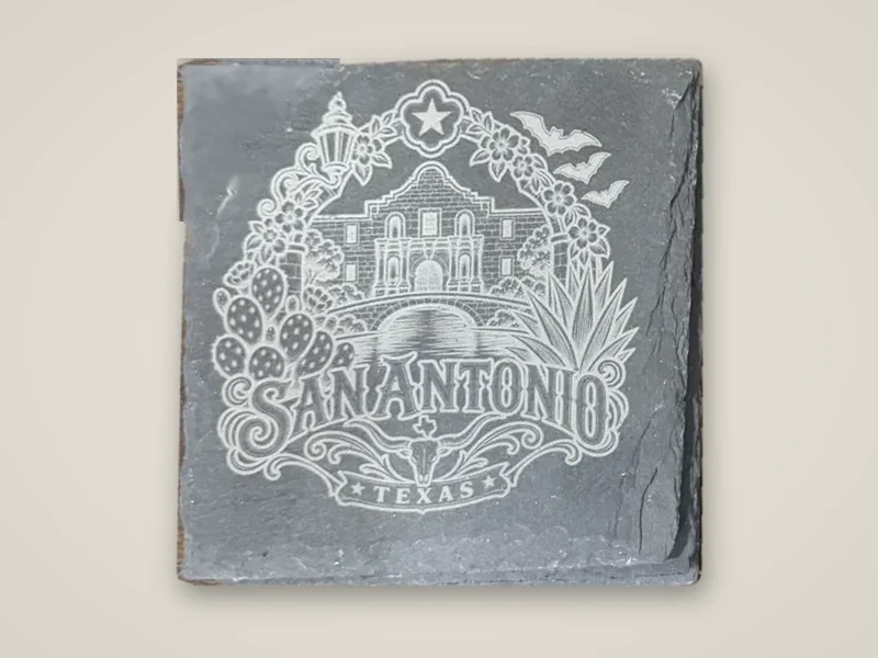 Slate coaster engraved with the Alamo, flowers and cactus and the words San Antonio, Texas